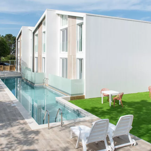 casa modular de diseño con piscina y amacas, jardín con mesas y sillas de terraza