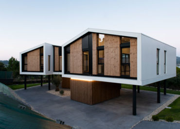vista general de una casa de diseño modular con acabados en madera e iluminada