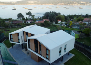 Vista general de una casa de diseño modular, en una playa con un paisaje de mar
